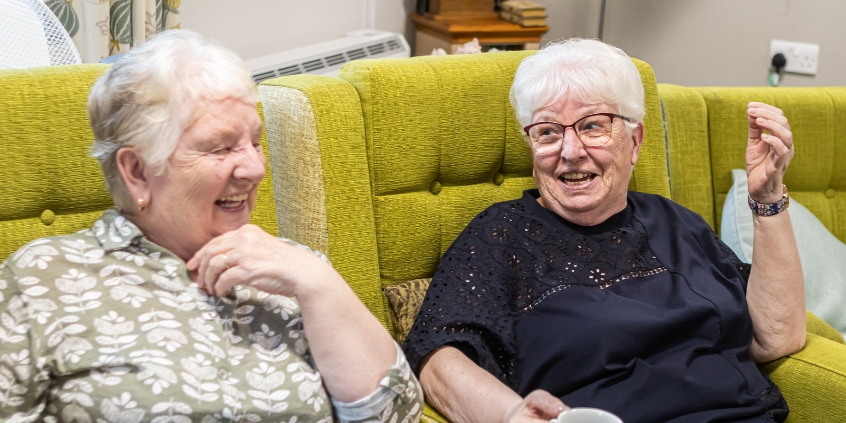 Two women chat and laugh together.