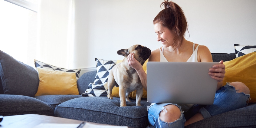 Woman sat on her sofa with her dog.